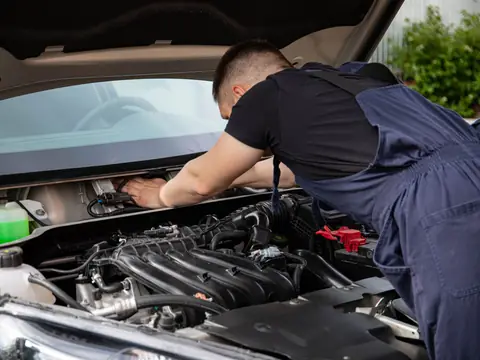 A technician leaning in under the windshield of a silver SUV