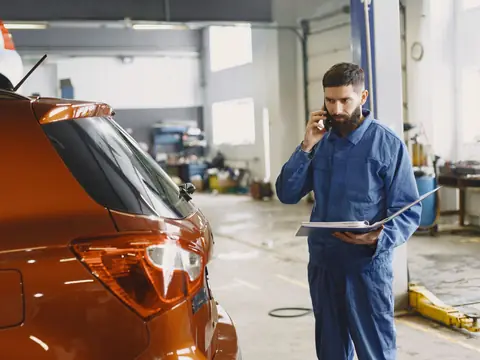 A technician on a phone call with a binder open in the shop